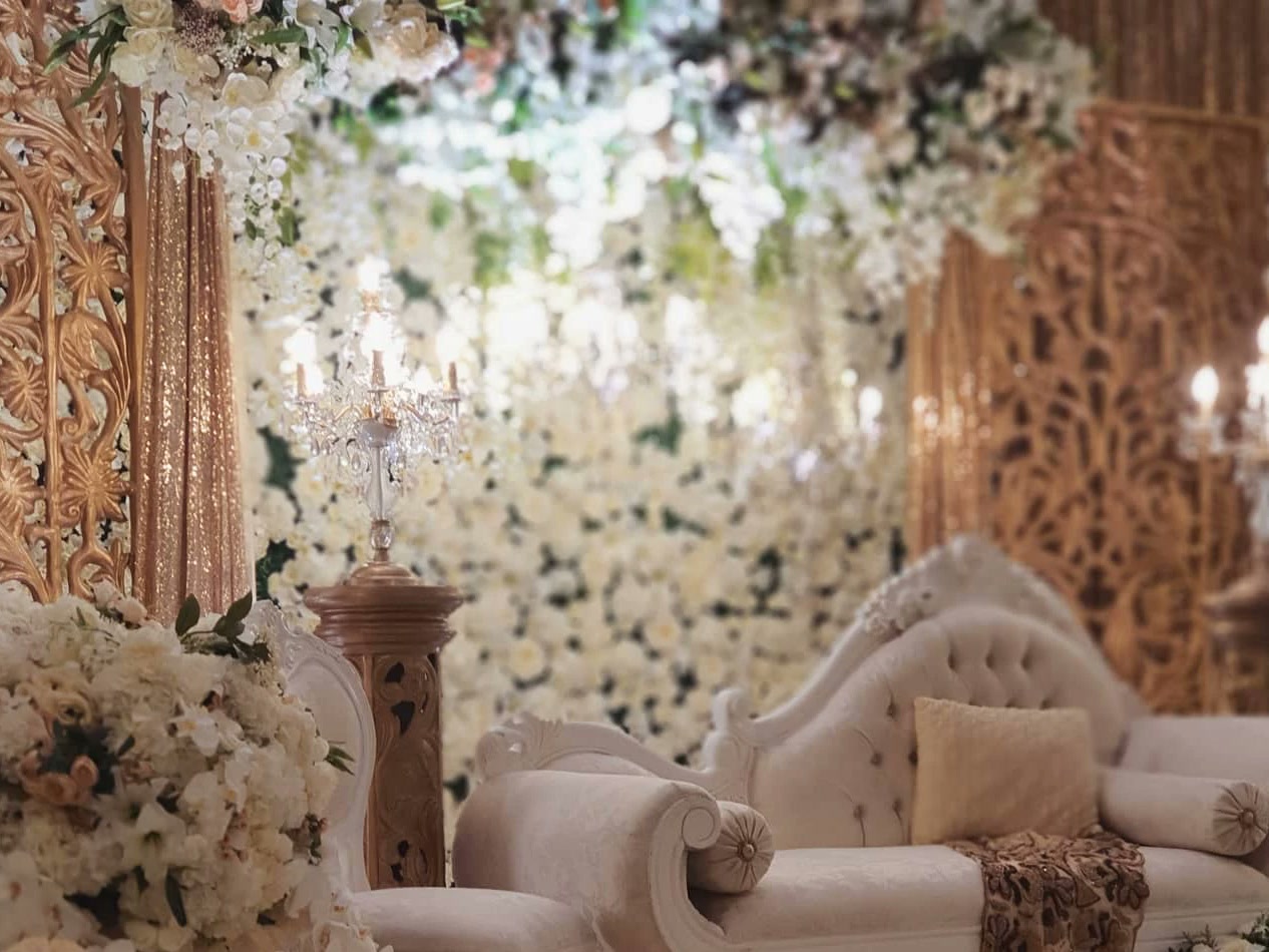Carved gold panels and a wall of ivory flowers behind a white chaise in the Ha'wa Mahal collection.